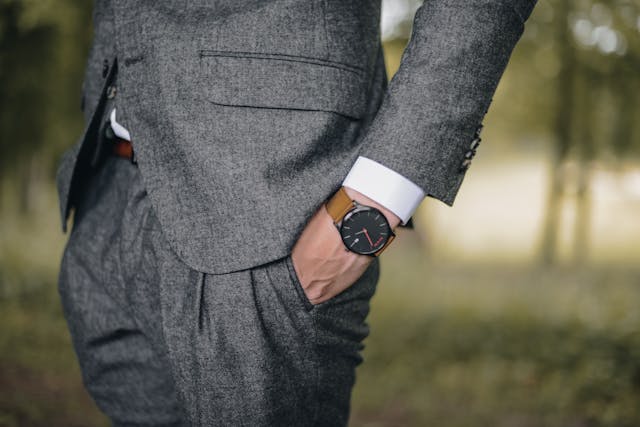 A well-dressed man holding his watch, wearing a suit and tie